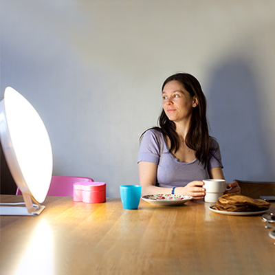 Woman using a therapy light while eating breakfast