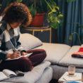 woman prepping for the week ahead, writing in journal on sofa