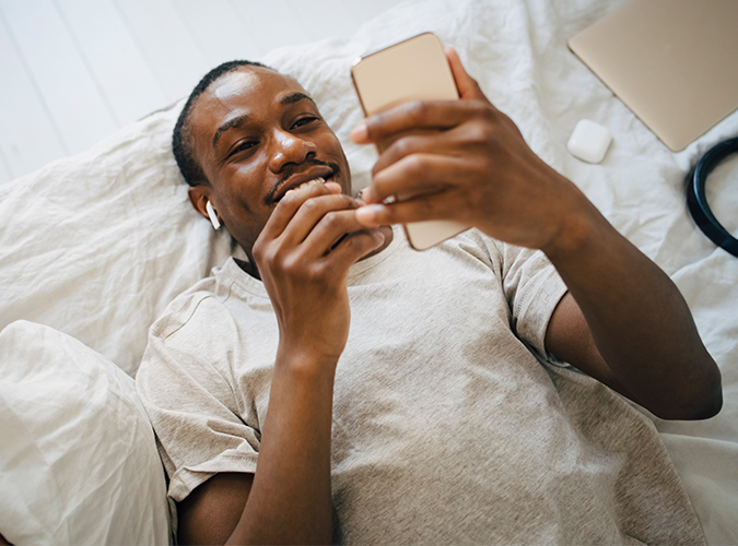man looking at phone in bed