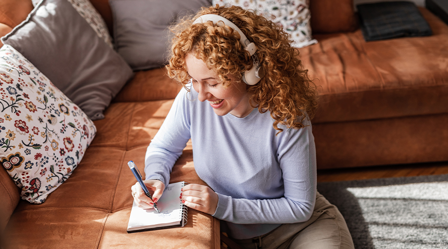 Woman listening with headphones and journaling